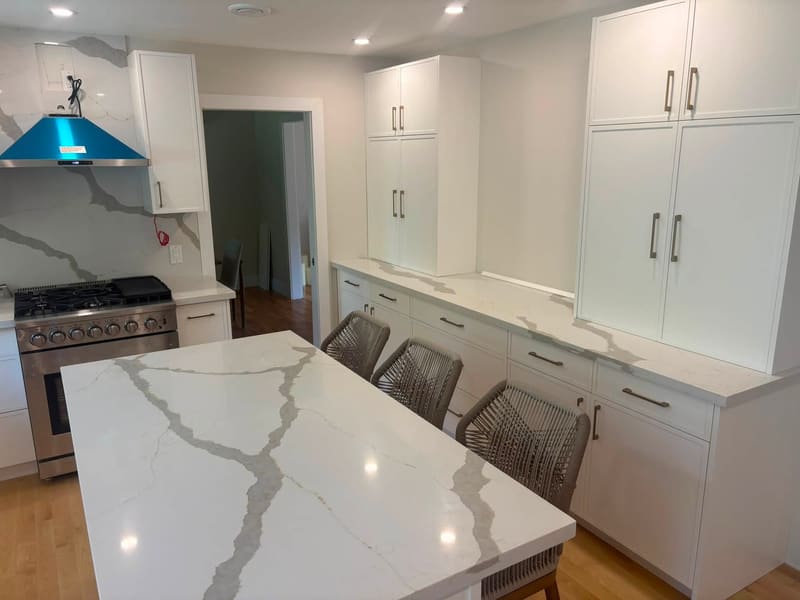 Calacatta-pattern quartz island with a waterfall end in a white kitchen