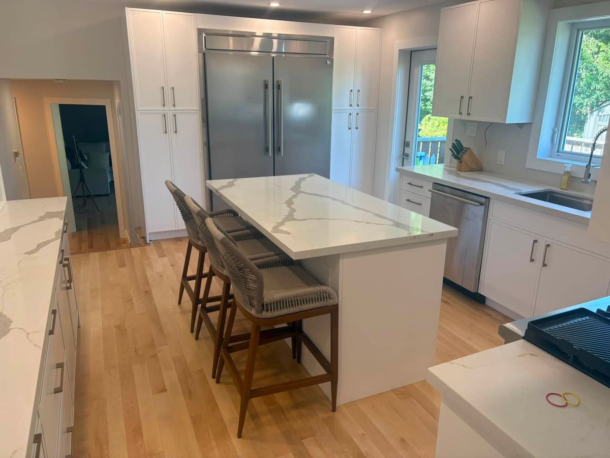 Long quartz island with seating in a bright open-plan kitchen